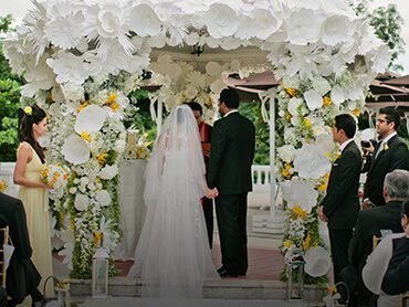 masterclass couple standing under white paper floral decorated pavilion